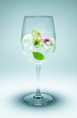 Wine glass with frozen flowers and water on grey background, concept of healthy lifestyle