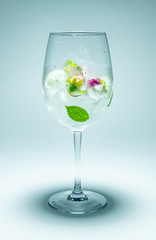 Wine glass with frozen flowers and water on grey background