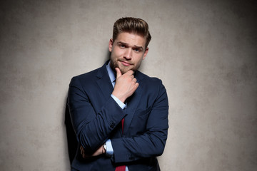 formal guy standing and touching chin thoughtful