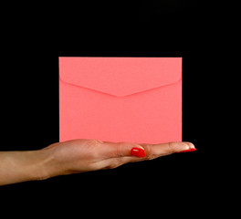 Fototapeta premium Woman hand palm shows pink envelope over black