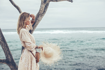 Boho model wearing dress and straw hat on the beach © Alena Ozerova