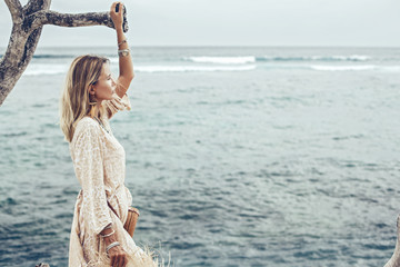 Boho model wearing dress and straw hat on the beach