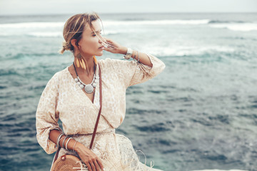 Boho model wearing dress and straw hat on the beach