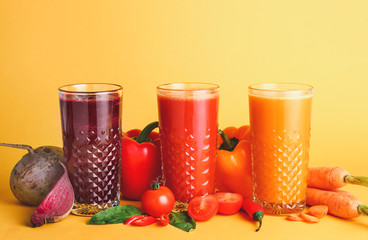 Glasses of fresh vegetable juices on color background