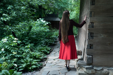 Woman with long hair in the village. Girl walks in the park. Back view