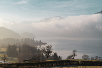 See Landschaft im Nebel mit Gebirge im Hintergrund