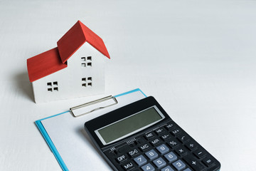 Miniature home, calculator and documents on white background. Sale contract concept. Top view