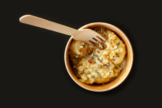 Fork in bowl with vegan meal in sustainable bamboo food packaging on black background. Eco-friendly disposable tableware and take-out packaging. Flay lay, top view image with selective focus.