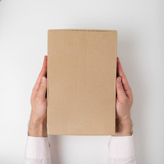 Rectangular box on men's hands on white background. Top view. Vertical frame
