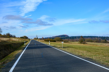 Lonely road through a green landscape, with many blue sky in the Rhoen, Bavaria, Germany