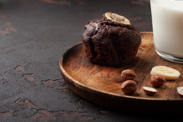 Chocolate muffin with milk and nuts on wooden plate. Close-up.