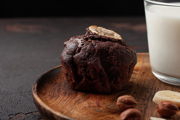 Chocolate muffin with milk and nuts on wooden plate. Close-up.
