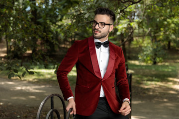businessman wearing red tuxedo standing supported on a fence