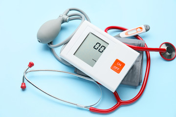 Electronic sphygmomanometer and thermometer on color background