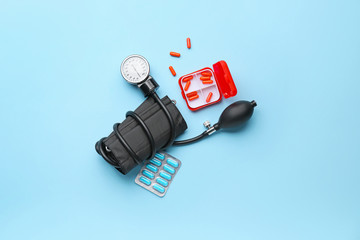 Composition with sphygmomanometer and pills on color background