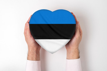 Flag of Estonia on a heart shaped box in a male hands. White background