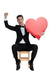 young elegant man celebrating victory and holding big heart