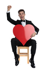 enthusiastic young groom holding big red heart