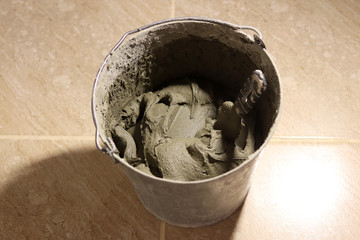repared cement in an old dirty iron bucket with a spatula. Selective focus. Home repair. Close-up...