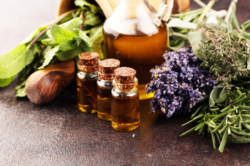 Fresh herbs from the garden and the different types of oils for massage and aromatherapy on table with lavender