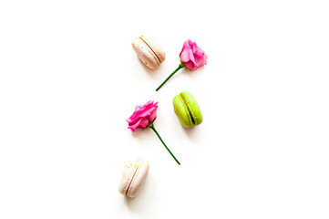 Festive composition. Multicolored macaroons and rose flowers on isolated white background.