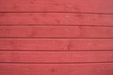 Wooden horizontal boards with cracks and knots are painted red. Background, texture.
