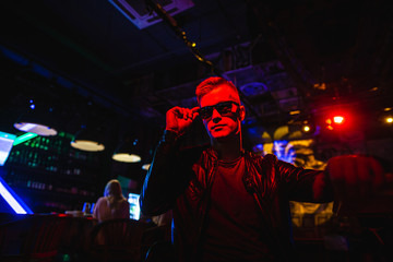 Handsome man in leather jacket with sunglasses and neon lights.