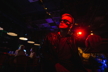 Handsome man in leather jacket with sunglasses and neon lights.