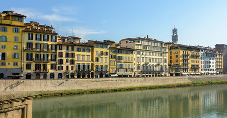 Arno River and the old promenade in Florence. Hazel houses with red roofs in Florence. Houses are reflected in the water.