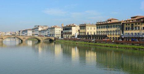 Fototapeta na wymiar Arno River and the old promenade in Florence. Hazel houses with red roofs in Florence. Houses are reflected in the water.