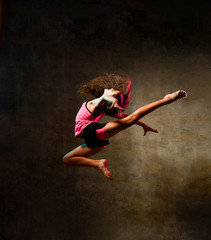 Street dance girl dancer jumping up dancing in neon light doing gymnastic exercises jump in studio...