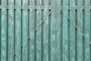 A fragment of a painted wooden gate. The structure of the boards and battens. Turquoise surround...