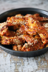 Selective focus. Appetizing buffalo wings in a pan. Baked chicken wings with sesame seeds.