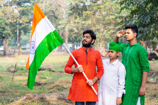 Three kids and young boys of different age and different religion hearing tricolor dress and holding Indian National flag. Indian kids celebrating Republic or Independence day of India.