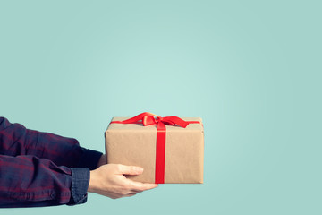 female hands giving gift box on green background