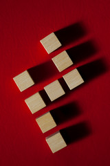 figura geometrica en forma de silla con cubos de madera sobre fondo rojo y sombras proyectadas