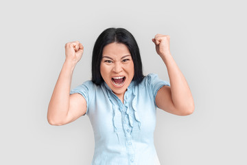 Freestyle. Asian woman standing isolated on white hands in fists shouting to camera emotional and expressive © Viktoriia