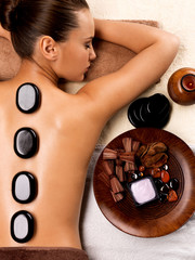 Beautiful woman relaxing in spa salon with hot stones on body.