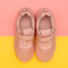 Pink sport shoes on colorful background. New sneakers on pink and yellow pastel background. Losing weight and sport concept. Top view, flat lay, square instagram format