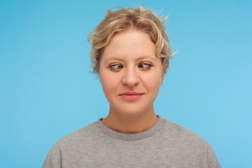 Portrait of amusing comic woman with short curly hair making silly face with crossed eyes, awkward...