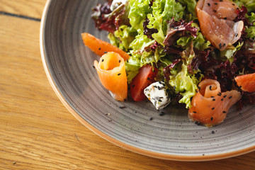 Lunch Time. Fresh salad with salmon and feta isolated on table close-up