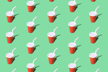 Red disposable cup for beverages with straw texture abstract on green.