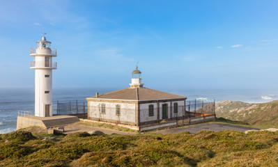 Fototapeta na wymiar The Tourinan lighthouse in Galicia in northern Spain. It is a sunny winter afternoon. The air is very hazy with a lot of spray from the Atlantic. There are high waves on the sea.