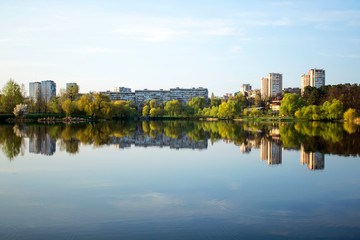 Fototapeta premium The lake is surrounded by spring trees and houses.