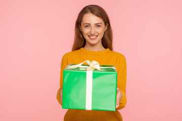 Portrait of cheerful pretty ginger girl holding big gift box and looking at camera with toothy smile, showing green present, greeting and celebrating holiday. studio shot isolated on pink background