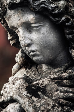 Close up fragment of an ancient statue of praying guardian angel. Religion tradition.