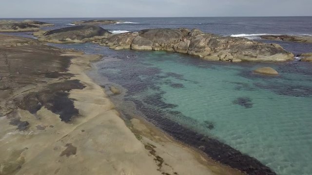 Plano de drone con grupo de personas nadando en el mar cerca de una playa de agua cristalina 4K
