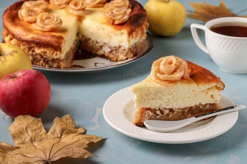 Cheesecake with apples and cup of coffee located on a light blue background, decorated with roses from apples, Horizontal orientation