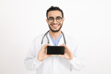 Cheerful young doctor with toothy smile photographing you on smartphone