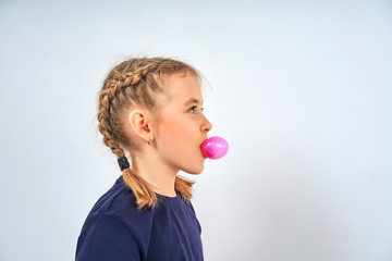 girl inflates a bubble of chewing gum on a white background